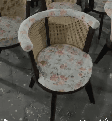 A stylish accent chair featuring a dark stained wooden frame, a rounded cane backrest, and a comfortably upholstered seat and top rail. The upholstery showcases a delicate floral pattern with pink, green, and orange hues on a light background. The chair is supported by four sturdy, tapered legs. — 3D model
