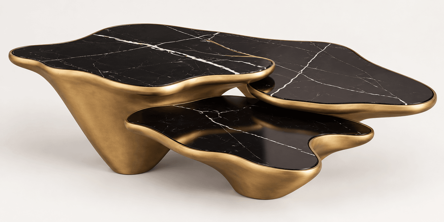 A contemporary set of three nesting tables, featuring organic, wavy-edged black marble tops with prominent white veining, supported by matching sculptural, brass-toned bases. The tables are designed to be arranged together, creating a layered, fluid aesthetic. — 3D model