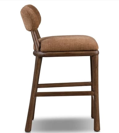 A contemporary bar stool featuring a dark stained wooden frame and upholstered seat and backrest. The backrest is distinctly curved and organic in shape, providing lumbar support. The seat is generously padded and rounded. The frame consists of four sturdy, tapered legs connected by integrated footrests for comfort and stability. The upholstery is a textured, rust-brown fabric, complementing the dark wood finish. — 3D model
