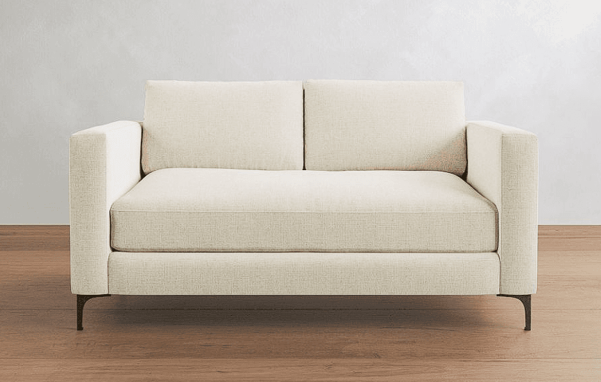 A modern two-seater loveseat featuring a cream or off-white textured fabric upholstery. It has straight track arms, loose back cushions, and a tight seat design. The frame is supported by slender, tapered dark metal legs. The overall aesthetic is clean and contemporary, suitable for various interior styles. — 3D model