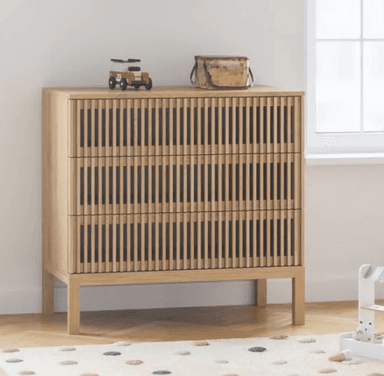 A modern chest of drawers featuring three drawers with a distinctive slatted wood front design. The piece is crafted from light-toned wood and stands on four simple, straight legs, creating an elevated and airy appearance. Its minimalist aesthetic emphasizes clean lines and natural materials. — 3D model