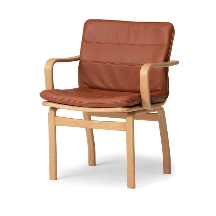 A modern armchair with a light wood frame and brown leather upholstery. The armchair features a gently curved backrest and seat cushions, along with curved armrests that flow from the backrest supports. The frame is constructed from light-colored wood, possibly oak or ash, with visible grain. The upholstery appears to be genuine leather, exhibiting a warm, reddish-brown tone and horizontal stitching details on the backrest cushion. The chair has four straight legs and a supportive base structure. — 3D model