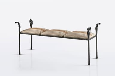 A distinctive figural wrought iron bench featuring a dark, textured metal frame with decorative uprights sculpted as human figures, supporting segmented upholstered cushions with a striped pattern. The bench has four slender legs and decorative arm-like elements at each end, also featuring figural motifs. — 3D model