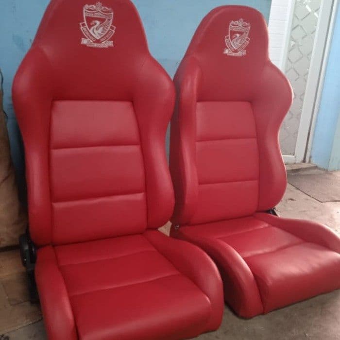 A single, bright red upholstered racing-style bucket seat, designed for high support and comfort, typically for automotive or simulation use. It features pronounced side bolsters, an integrated headrest, and an embroidered emblem on the headrest. — 3D model