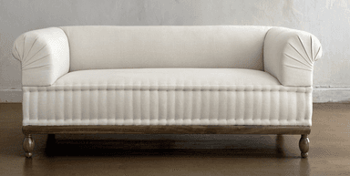 A cream-colored upholstered daybed with a rolled armrest and a tufted lower section. The daybed is supported by a dark wooden frame and features turned wooden legs. — 3D model