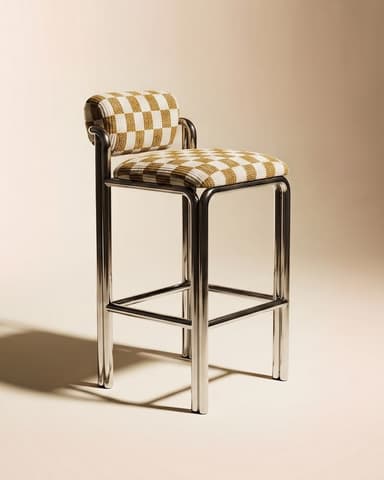 A modern bar stool featuring a sleek, tubular chrome frame and a distinctive checkered upholstered seat and backrest. The frame forms a continuous loop for the legs and incorporates a footrest. The upholstery is a textured fabric in alternating cream and light yellow/beige squares, covering a padded seat and a cylindrical backrest. — 3D model