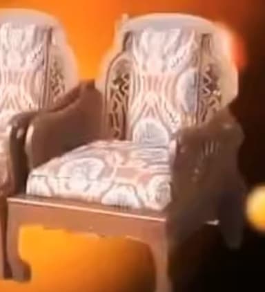 A traditional wooden armchair featuring an intricately carved frame, upholstered seat and back cushions, and cabriole legs. The wood has a dark finish, and the cushions are covered in a patterned fabric. — 3D model