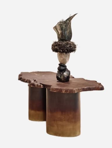 A coffee table with a live-edge, irregular-shaped wooden top supported by two cylindrical, gradient-colored bases. The table top features a natural, organic edge. A sculptural element made of stacked stones and natural materials is placed on one side of the table. — 3D model