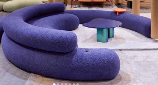 A modular, curved sofa with a vibrant purple upholstery. The sofa is composed of several individual, rounded sections that connect to form a continuous seating unit. Each section features a plush, padded surface, and the overall design is organic and contemporary. — 3D model