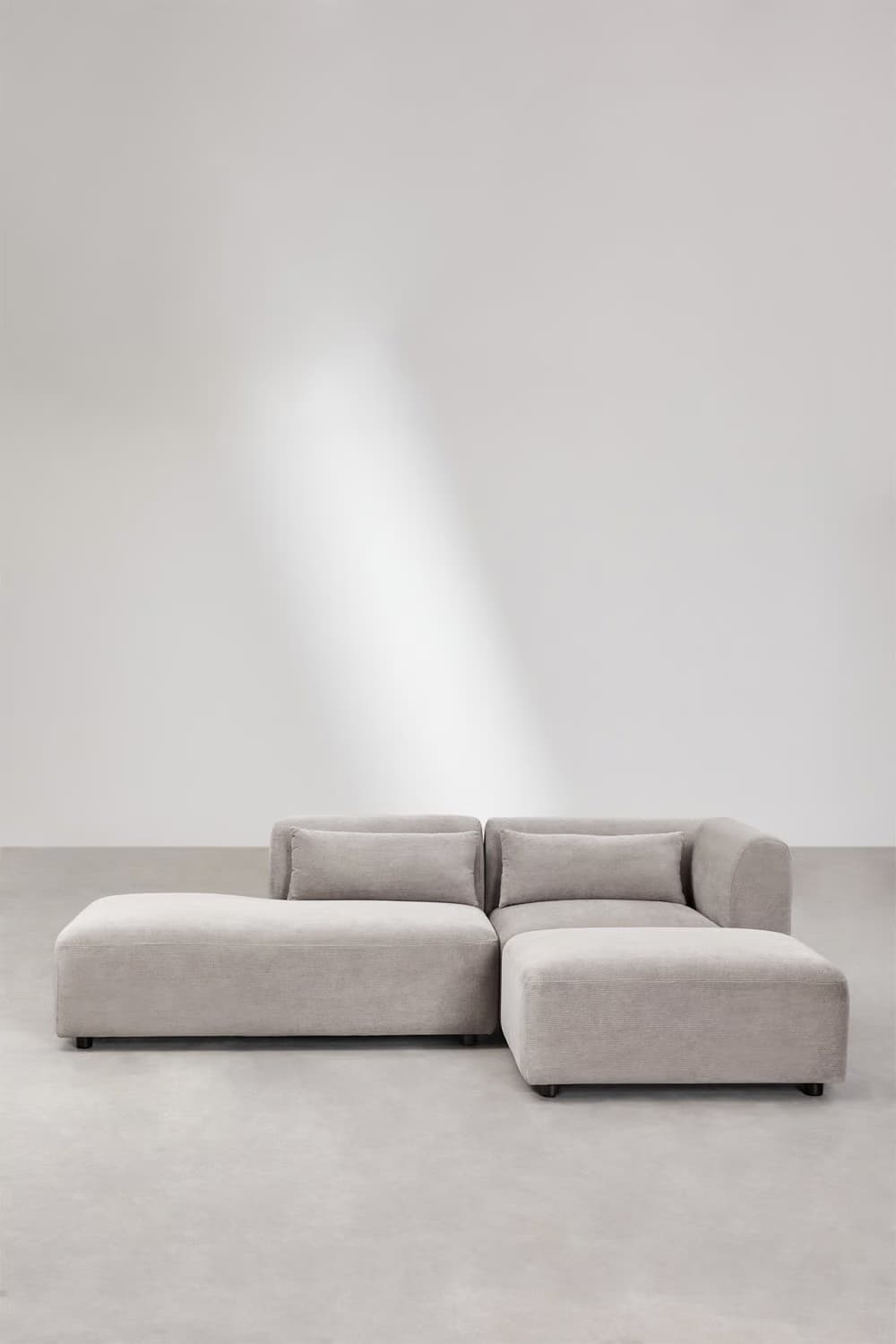 A contemporary sectional sofa with a chaise lounge extension and an ottoman. The sofa features plush cushions and a low-profile design with clean lines. — 3D model