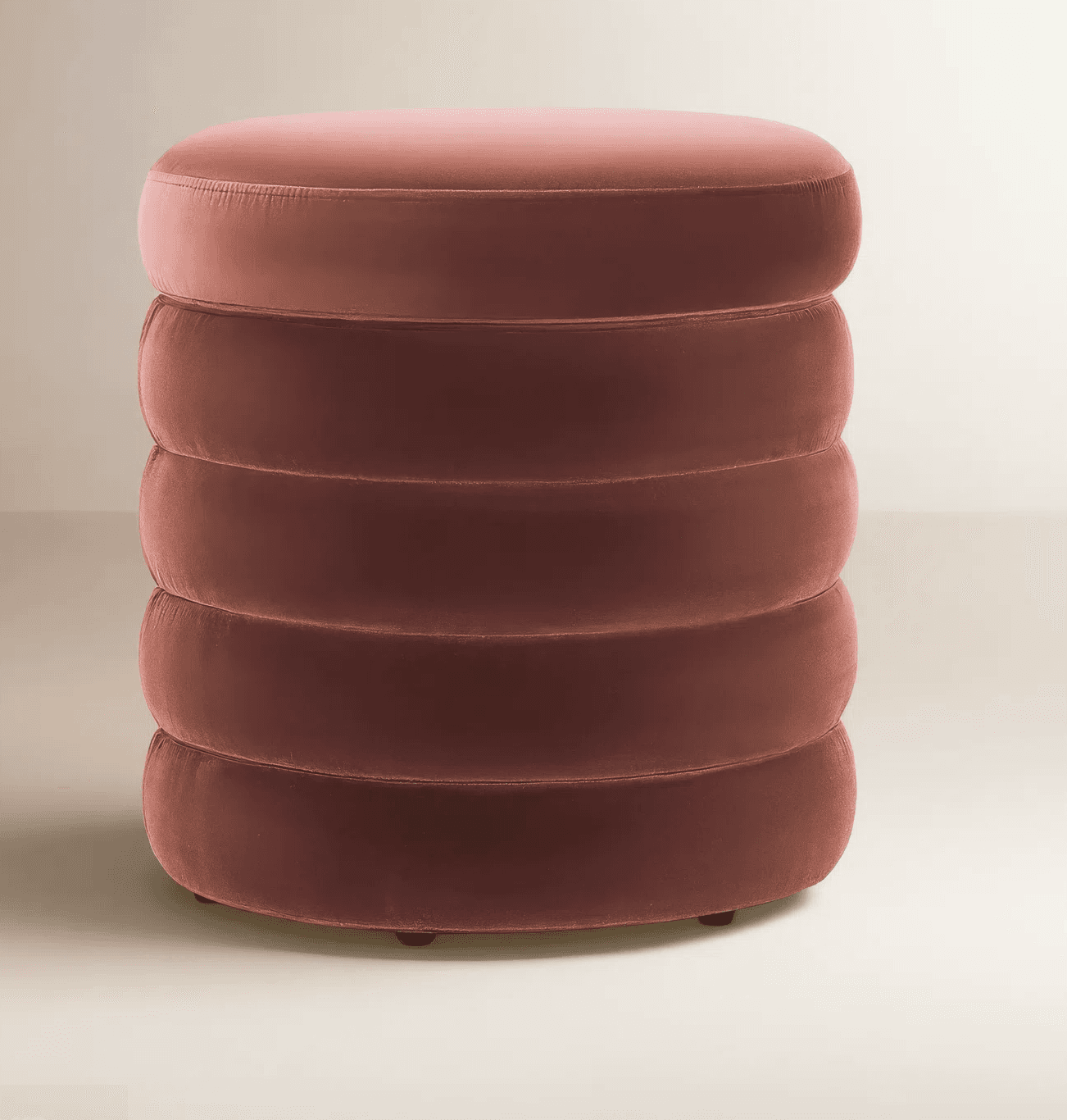 A cylindrical ottoman with a plush velvet upholstery. The body of the ottoman is segmented into five distinct horizontal sections, creating a stacked appearance. The top surface is flat and round, complementing the overall cylindrical form. — 3D model