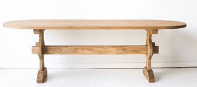 An oval dining table constructed from light-toned wood, featuring a distinctive trestle base. The tabletop is smooth and has rounded edges, while the base consists of two pedestals connected by a stretcher, presenting a sturdy and classic design. — 3D model