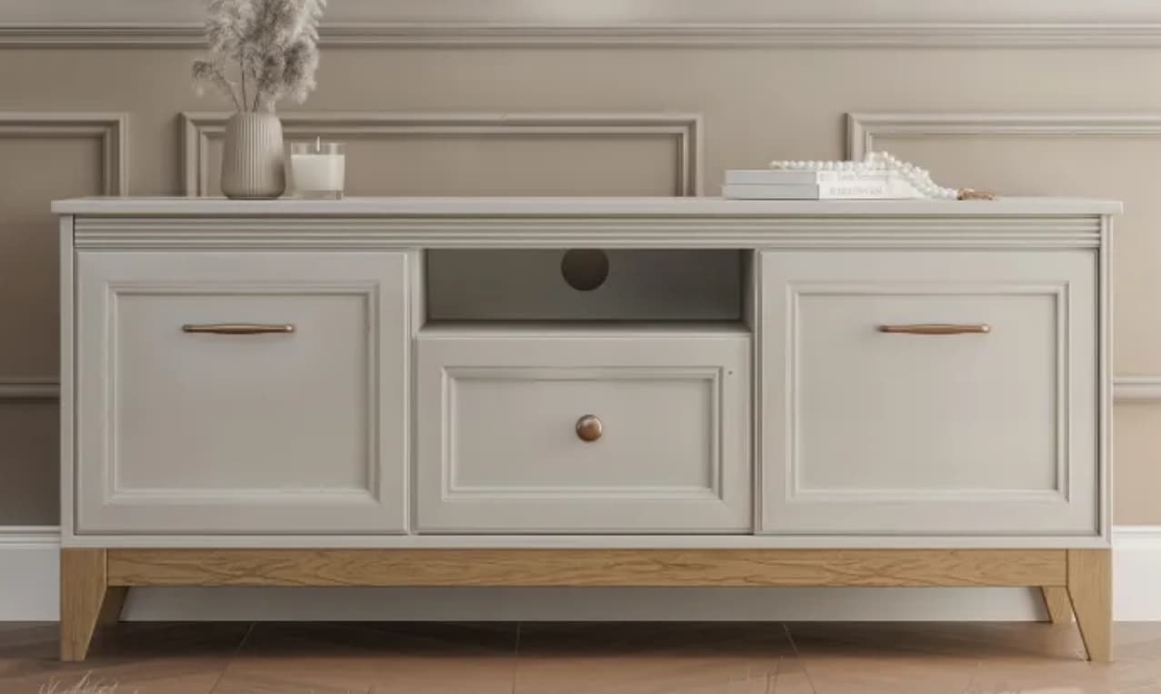 A transitional style media console or TV stand featuring a light gray painted finish, paneled doors, a central open shelf, a drawer, and a contrasting natural wood base with splayed legs. — 3D model