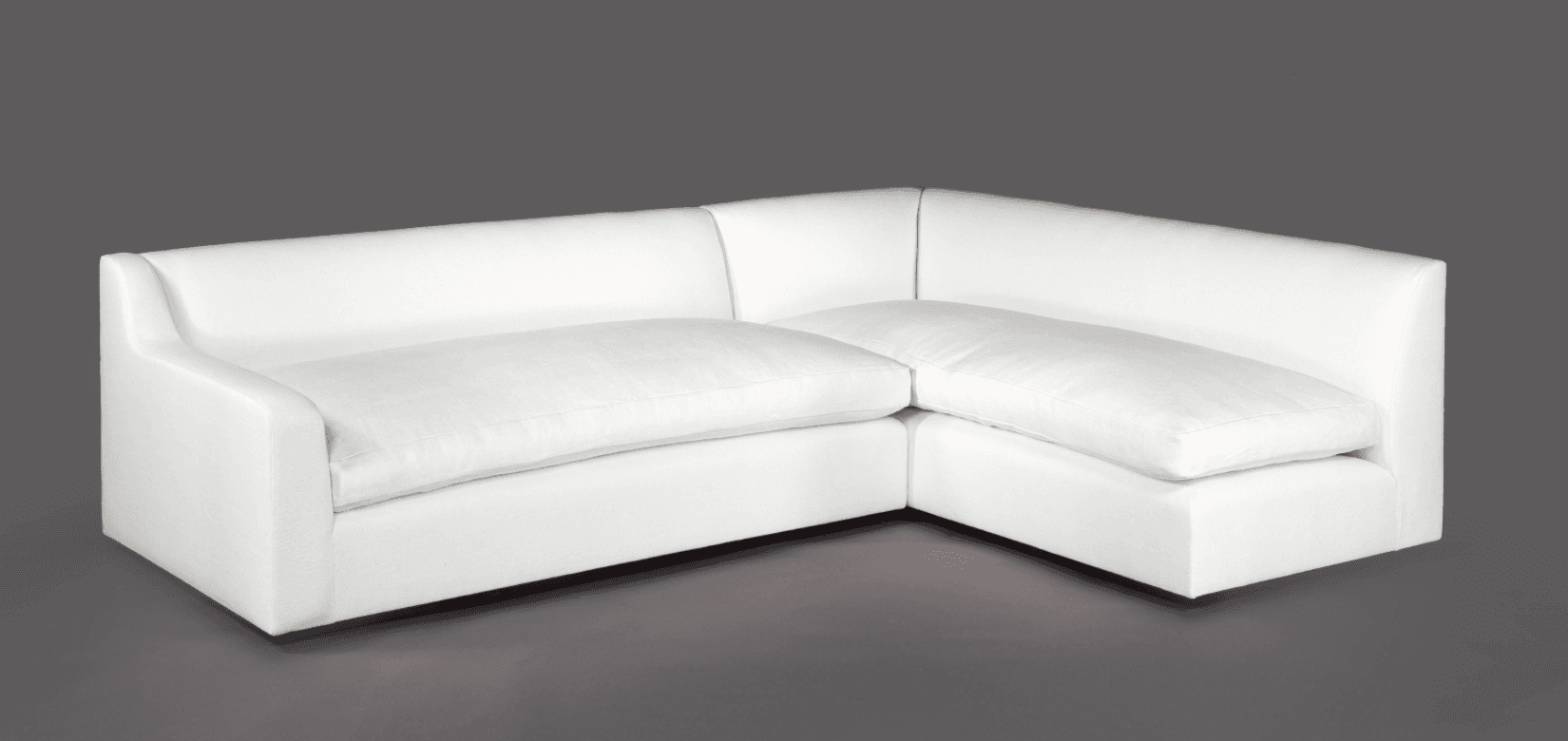 A white L-shaped sectional sofa with deep seating and clean lines. The sofa features a low profile with broad arms and a square base. The cushions appear plush and are upholstered in a smooth fabric. — 3D model