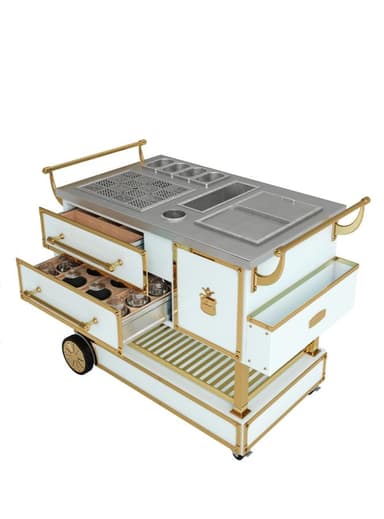 A multi-functional serving cart with a stainless steel top featuring integrated compartments, a grill grate, and drawers. The cart has a white body with gold-toned trim and handles, and it is equipped with wheels for mobility. The drawers are designed for storage, with one drawer holding various glass containers. — 3D model