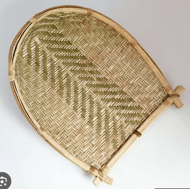 A traditional handwoven bamboo winnowing basket, characterized by its shallow, scoop-like form with a flat base and raised, curved edges. The weave features a distinct herringbone pattern created by alternating lighter and slightly darker bamboo strips, suggesting different natural shades or processing. The rim is reinforced with thicker bamboo strips, and the corners or handles are secured with wrapped twine. — 3D model