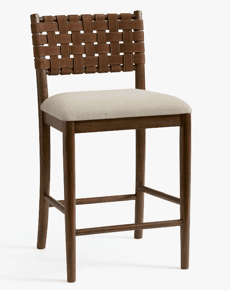 A bar stool featuring a dark wood frame, a woven brown leather backrest, and a light-colored upholstered seat. It has integrated footrests and tapered legs. — 3D model