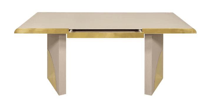 A contemporary desk featuring a rectangular tabletop with a light beige finish and a brass trim along the edges. It has two substantial, rectangular legs that are also light beige and are accented with brass geometric inlays. A single drawer is integrated into the center of the tabletop, with its brass front partially visible. — 3D model