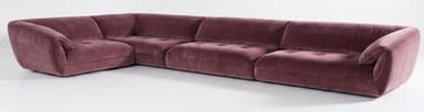An L-shaped modular sectional sofa upholstered in a plush, mauve-colored velvet fabric. The sofa features a low-profile design with subtly rounded edges and a hidden base, giving it a substantial yet integrated appearance. It is composed of multiple individual modules, including a corner piece and several straight segments, creating a continuous seating arrangement. The seat cushions exhibit a gentle button tufting, contributing to its luxurious and contemporary aesthetic. The overall impression is one of comfort and modern elegance. — 3D model