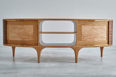 A contemporary media console crafted from walnut wood, featuring a long, low profile with two enclosed compartments and a central open shelving unit. The doors are sliding, with distinctive reeded details on their curved ends and prominent wood grain. The entire piece is supported by elegant, tapered legs. — 3D model