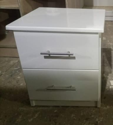 A compact, modern white nightstand featuring two drawers. It has a clean, minimalist design with a flat top surface, sleek silver-tone bar handles on each drawer, and a recessed plinth base. The overall aesthetic is simple and functional, suitable for contemporary interiors. — 3D model