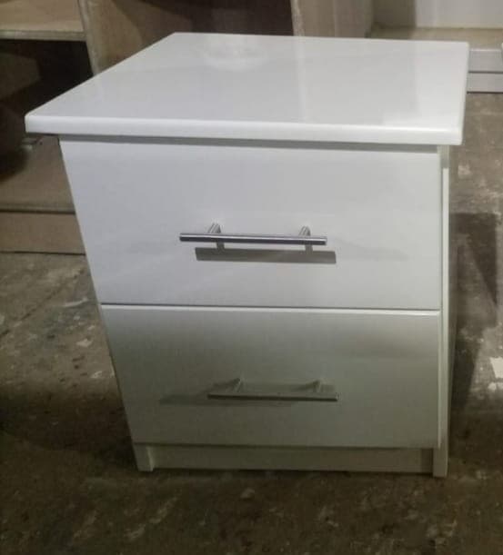 A compact, modern white nightstand featuring two drawers. It has a clean, minimalist design with a flat top surface, sleek silver-tone bar handles on each drawer, and a recessed plinth base. The overall aesthetic is simple and functional, suitable for contemporary interiors. — 3D model