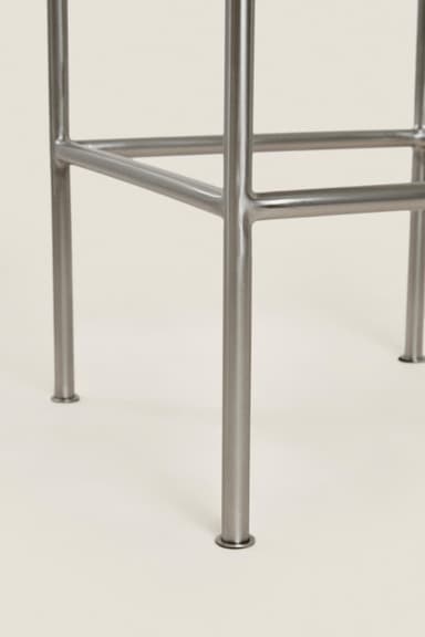 A minimalist, rectangular stool constructed entirely from brushed metal, featuring a seat with gently rounded corners and a tubular frame with integrated horizontal support bars. — 3D model