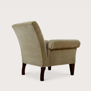 A fully upholstered armchair featuring distinct rolled arms and exposed dark wooden legs. The chair is covered in a soft, plush fabric, likely velvet or velour, in a muted, light greenish-beige color. Its back is gently reclined, and the seat appears well-cushioned, suggesting comfort. The legs are tapered and rectangular. — 3D model