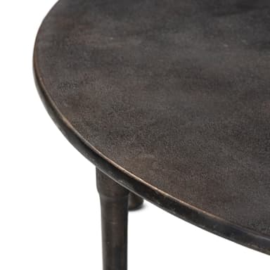 A round coffee table with a dark, textured top and a base constructed from four metal legs connected by intersecting crossbars. The legs are segmented with decorative bulbous elements and taper to a rounded foot. — 3D model