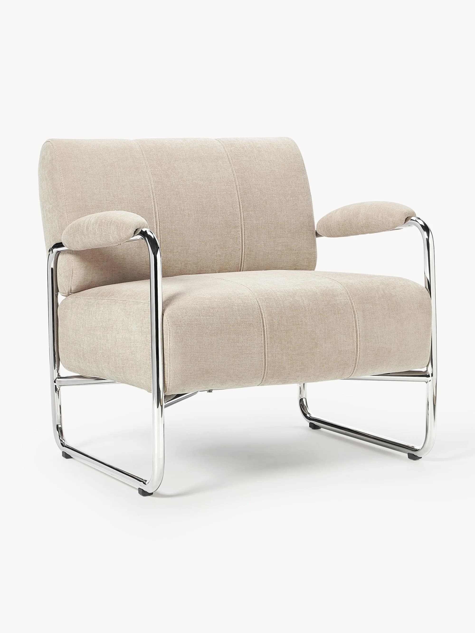 A modern lounge chair featuring a beige textured fabric upholstery and a polished tubular chrome frame. The chair has a low profile, with wide seat and back cushions exhibiting vertical panel stitching. The armrests are softly padded and covered in matching fabric, resting on the curved chrome frame. The base consists of continuous chrome tubing that forms the legs and supports, giving it a minimalist and contemporary aesthetic. — 3D model