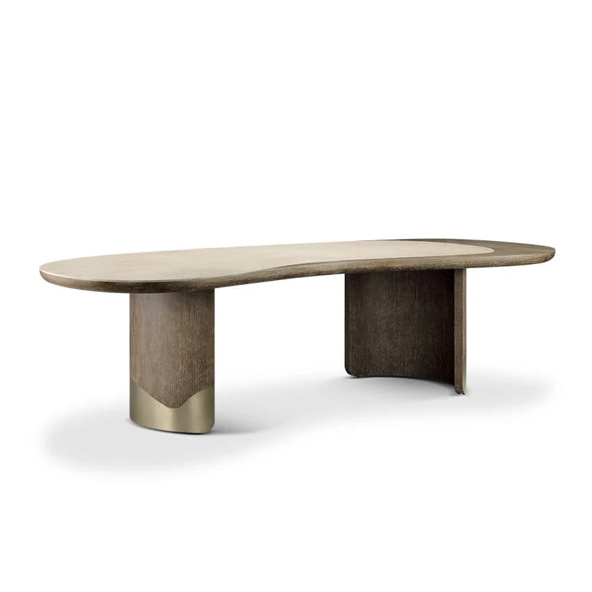 An oval-shaped dining table with a light-colored, smooth tabletop and a dark, textured wooden base. The base consists of two thick, curved legs that support the tabletop. Each leg has a metallic accent at its bottom, appearing to be brass or a similar gold-toned metal. — 3D model