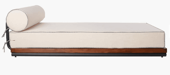 A modern daybed featuring an off-white upholstered mattress with visible black stitching, a matching cylindrical bolster pillow, a dark wooden platform, and a minimalist black metal base. — 3D model