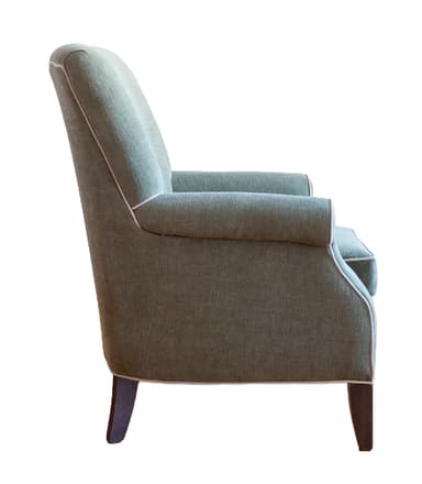 An upholstered armchair featuring a high back, classic rolled arms, and a single loose seat cushion, all covered in a textured sage green fabric. The armchair is accented with white contrast piping along its edges and stands on four dark, gently tapered wooden legs. — 3D model