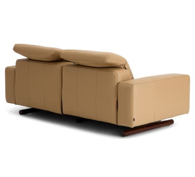 A modern two-seater reclining sofa, upholstered in smooth, light tan leather. It features two individual seats, each with a plush back cushion and integrated armrests. The sofa stands on small, dark-colored cylindrical feet, offering a minimalist profile. — 3D model