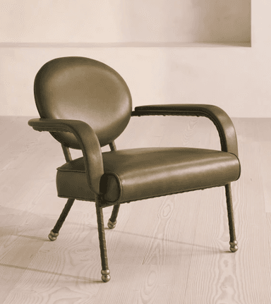 A contemporary armchair with a rounded backrest and armrests, upholstered in a muted olive-green material. The frame appears to be made of metal with a dark finish, and the legs are slender with decorative brass caps. — 3D model