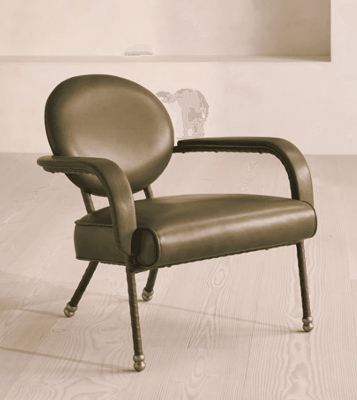 A contemporary armchair with a rounded backrest and armrests, upholstered in a muted olive-green material. The frame appears to be made of metal with a dark finish, and the legs are slender with decorative brass caps. — 3D model