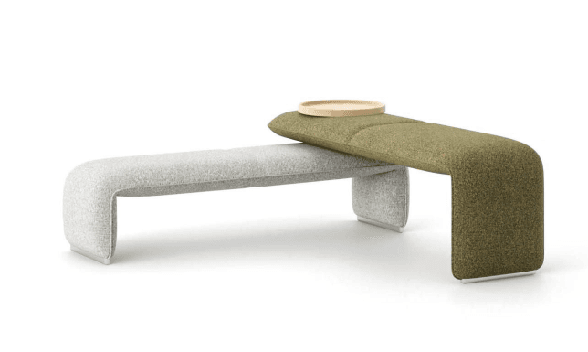 A modern, modular bench with two distinct upholstered sections. The left section is a low bench with a smooth, continuous curved base in a light gray textured fabric. The right section is a higher, elongated element upholstered in a speckled green textured fabric, curving downwards to meet the base of the left section. A light wood tray rests on top of the green upholstered section. The bench appears to be constructed with a solid internal frame and upholstered padding. — 3D model