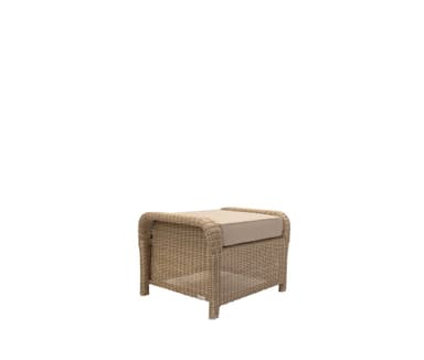 A rectangular outdoor ottoman featuring a woven wicker frame in a light brown or beige tone, topped with a thick, removable beige fabric cushion. The wicker extends down to form integrated low feet, and the construction suggests durability for exterior use. — 3D model
