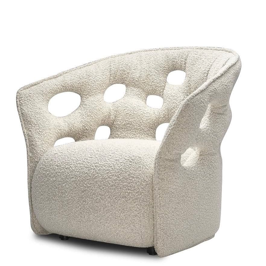 A cream-colored armchair with a curved back and seat. The upholstery features a textured boucle fabric. The backrest and armrests are adorned with a series of irregular, rounded cutouts, creating a distinctive aesthetic. The chair sits on short, dark-colored legs. — 3D model