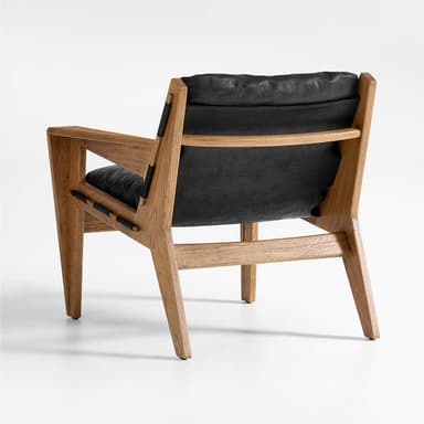 A modern armchair with a solid wood frame and black leather cushions. The frame features a clean, angular design with visible wood grain. Black leather straps are integrated into the sides of the frame, connecting the seat and back support elements. The armchair includes a plush seat cushion and a separate back cushion. — 3D model