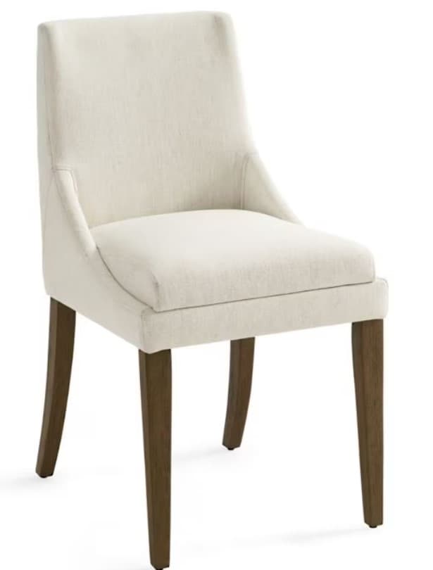 A cream-colored upholstered dining chair with a slightly curved backrest and wooden legs. The upholstery appears to be a textured fabric, possibly linen or a linen blend. The chair has a simple, elegant design suitable for a dining room or accent seating. — 3D model