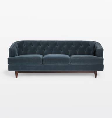A three-seater sofa with a tufted back and seat cushions. The sofa features a rounded armrest profile and is supported by tapered wooden legs. The upholstery appears to be a dark teal or navy blue velvet fabric. — 3D model