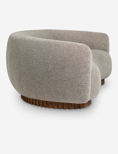 A curved sofa with a rounded silhouette, featuring a textured fabric upholstery and a distinctive wooden base with vertical fluting. The sofa has integrated armrests that flow into the backrest, creating a continuous, organic form. The base is composed of numerous closely spaced, vertical wooden elements. — 3D model
