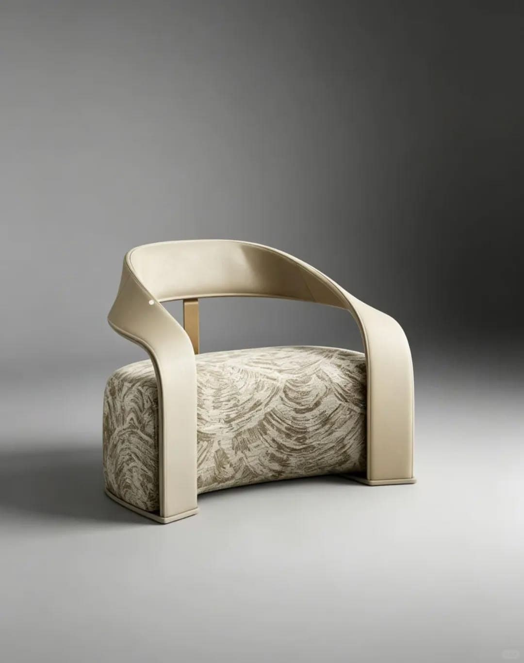 A modern sculptural accent chair featuring a distinctive design. The seat and lower body are upholstered in a patterned fabric with abstract, wave-like motifs in beige and taupe. The backrest and armrests are formed by a continuous, elegantly curved band of solid cream or off-white upholstery. A subtle gold-finished metal element is visible as a structural support behind the upper backrest. The chair rests on its upholstered base. — 3D model