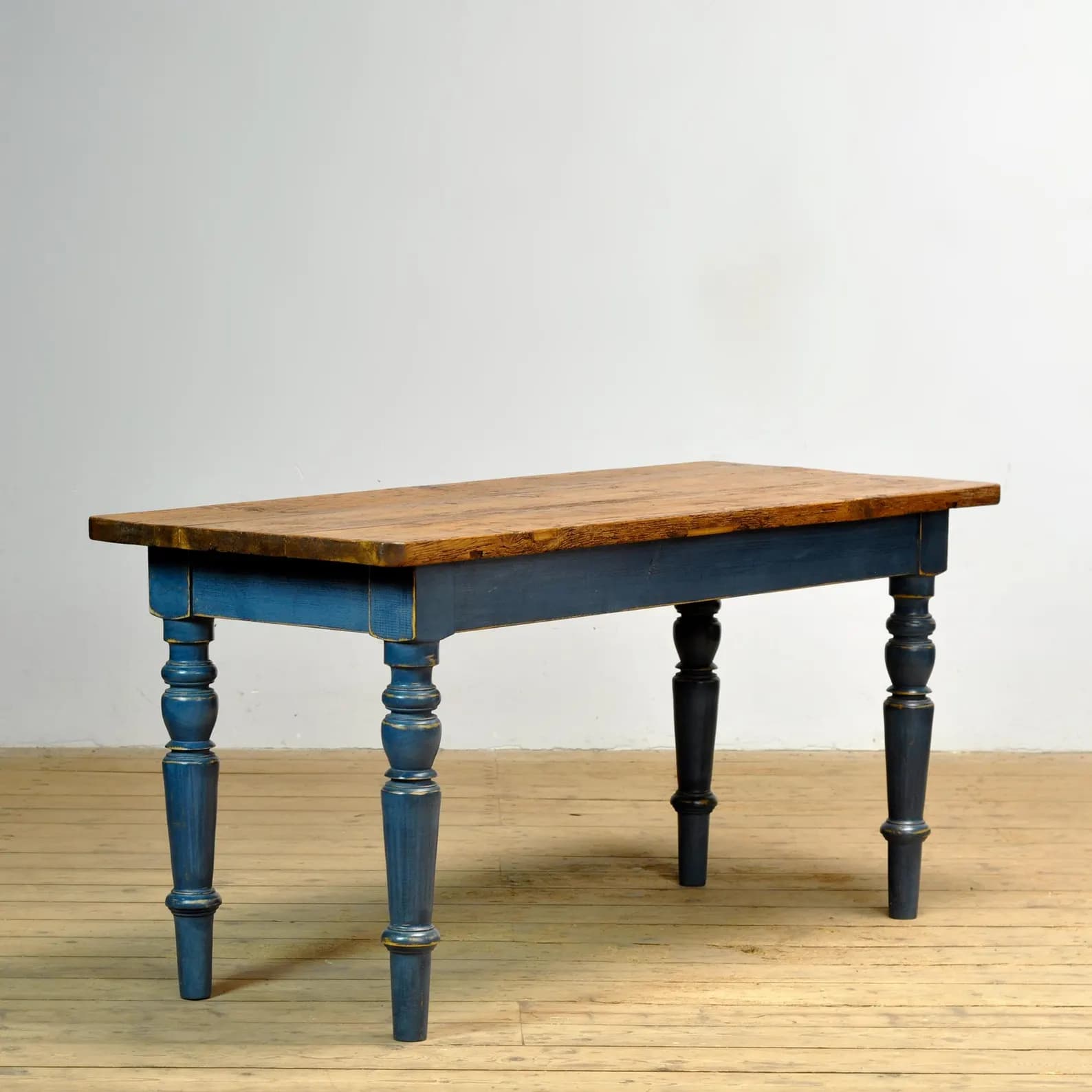 A long rectangular wooden bench featuring a natural wood top and a distressed dark blue painted base with intricately turned legs. — 3D model