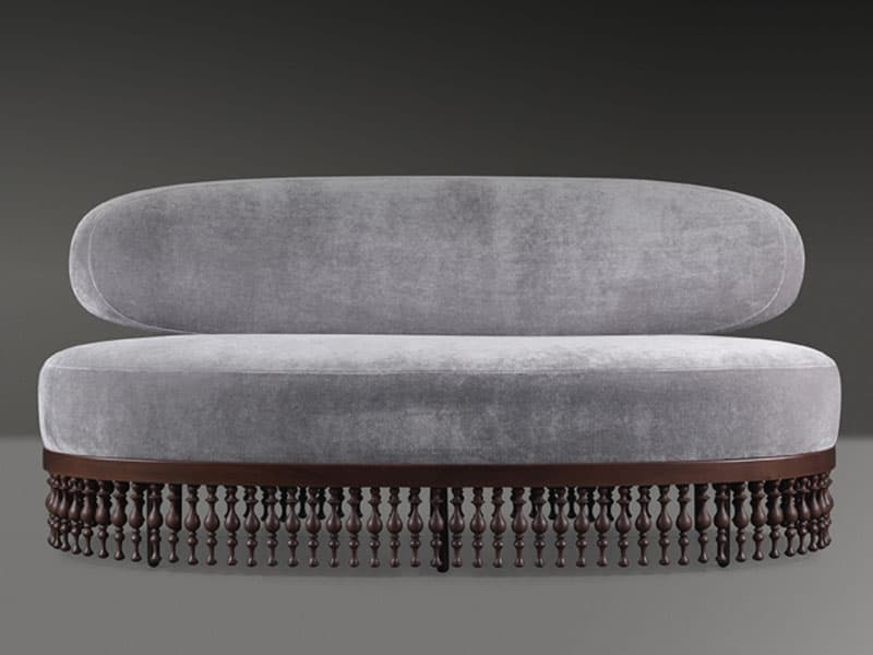 An elongated, asymmetrical chaise lounge upholstered in light grey velvet, featuring a single, organically curved backrest. The base is crafted from dark wood, showcasing a prominent border of turned wooden spindles or finials, which lends a decorative and classical touch to the overall modern form. The piece is designed for lounging or reclining. — 3D model