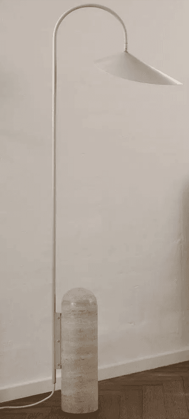 A modern floor lamp featuring a curved white metal stem extending from a cylindrical travertine base, topped with a broad, conical white metal shade. The lamp includes a white power cord with an inline switch. — 3D model
