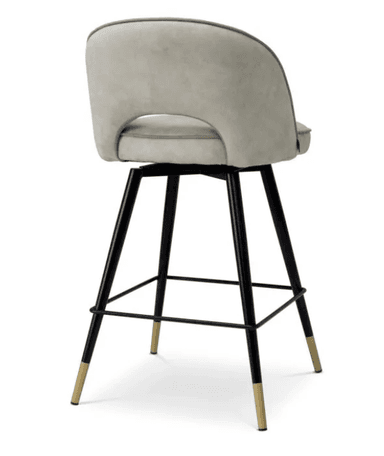 A contemporary bar stool featuring a comfortable upholstered seat and a curved backrest with a distinctive cutout detail. The seat swivels 360 degrees. It is supported by four splayed black metal legs, interconnected by a circular footrest, and finished with elegant brass-capped feet. — 3D model