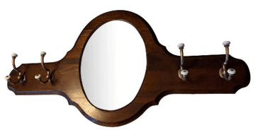 A wall-mounted decorative wooden panel featuring an oval mirror in the center and multiple brass coat hooks with white ceramic knobs on either side. The dark-finished wood frame has carved details along its edges. — 3D model