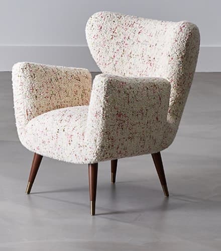 A vintage armchair with a high, wingback-style back and integrated arms. The upholstery has a textured, bouclé appearance with a predominantly cream base and speckles of pink and red. It is supported by four tapered wooden legs with brass ferrules at the feet. — 3D model